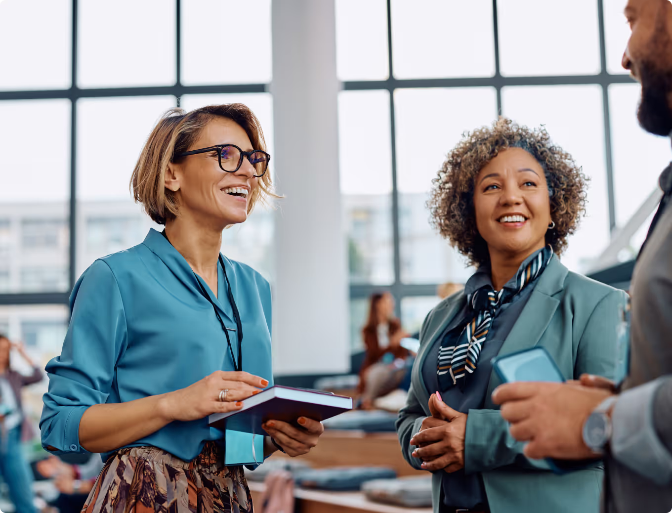 Two women in blue shirts and glasses are talking to each other.