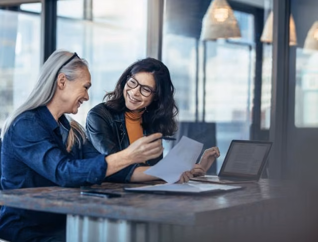 Two colleagues reviewing a report together at a laptop.